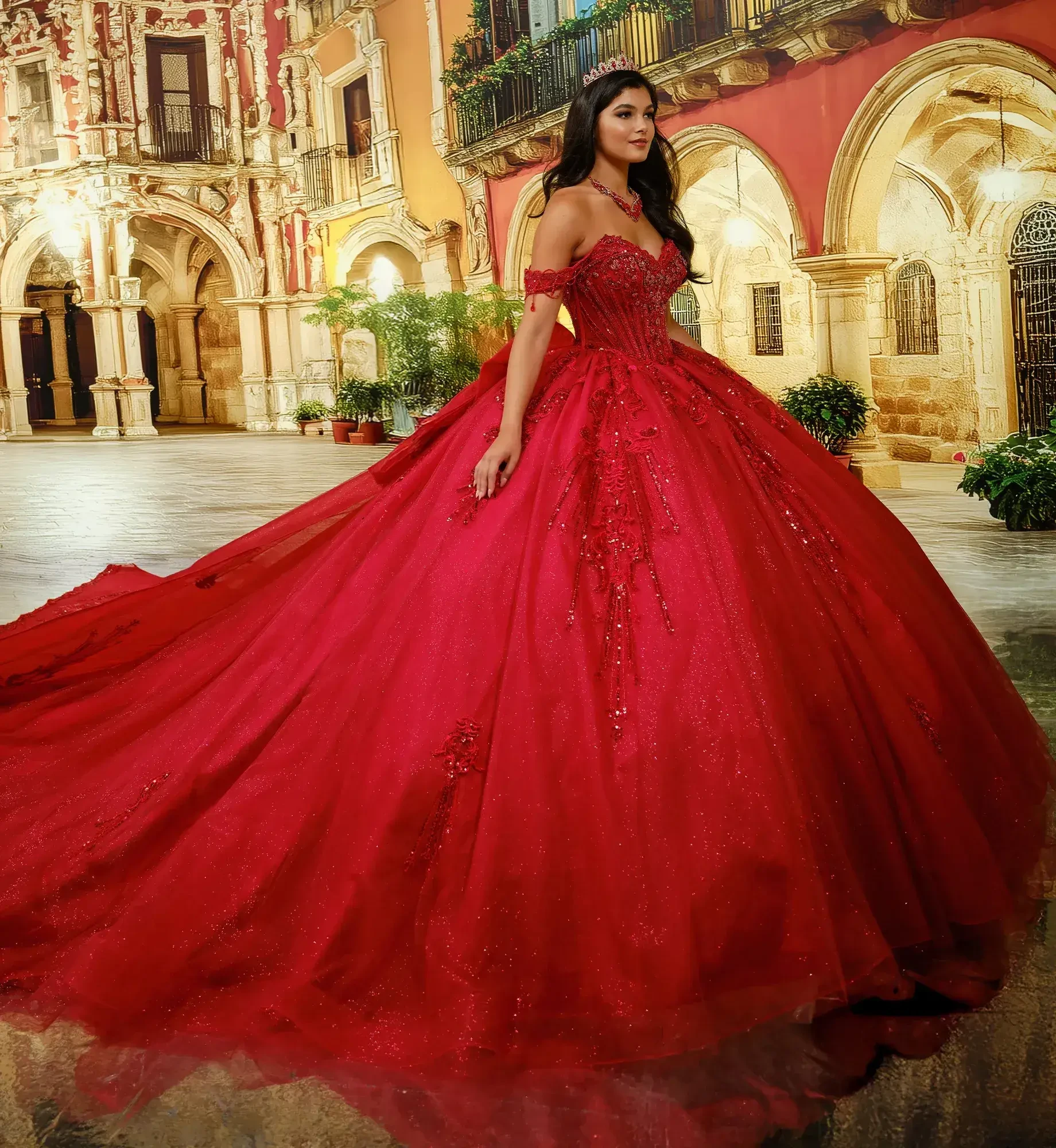 A woman wearing an elegant red ball gown with intricate details and a long train, standing in a beautifully decorated courtyard.